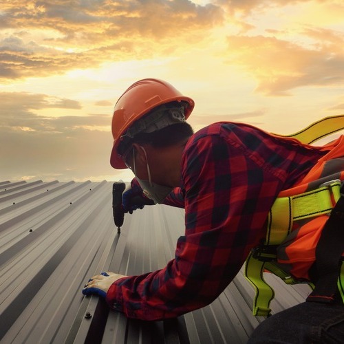 Roofer installs metal roof.