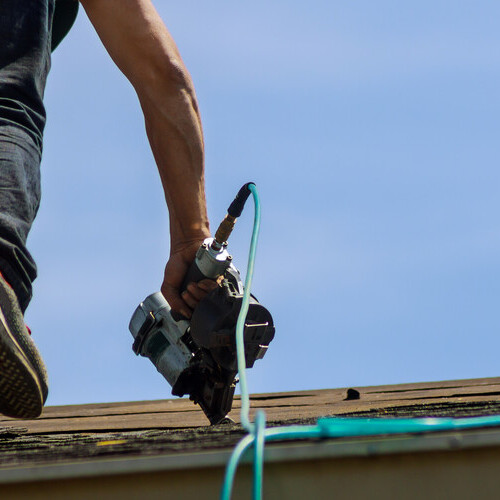 Roofer installs shingles.