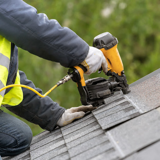 Roofer nails in shingles.